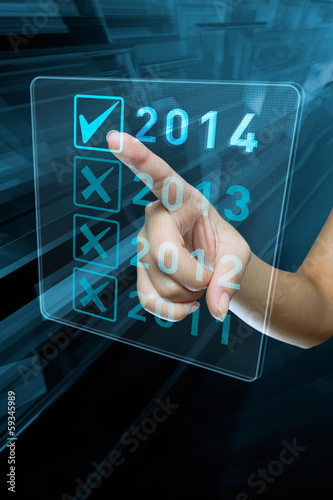 A woman hand selects 2014 on a digital screen photo