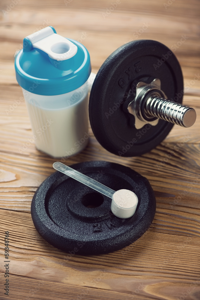 Bodybuilding supplement and a dumbbell, vertical shot Bodybuilding supplement and a dumbbell, vertical shot