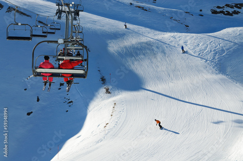 Skiers in a chair lift above the downhills
