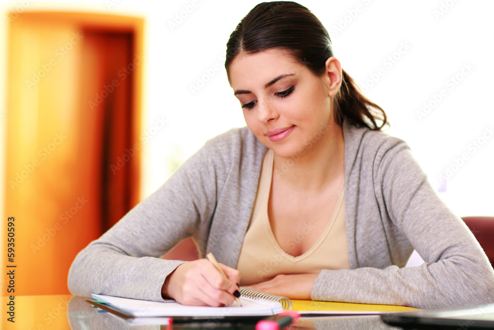 Young beautiful smiling woman writing notes at home Young beautiful smiling woman writing notes at home