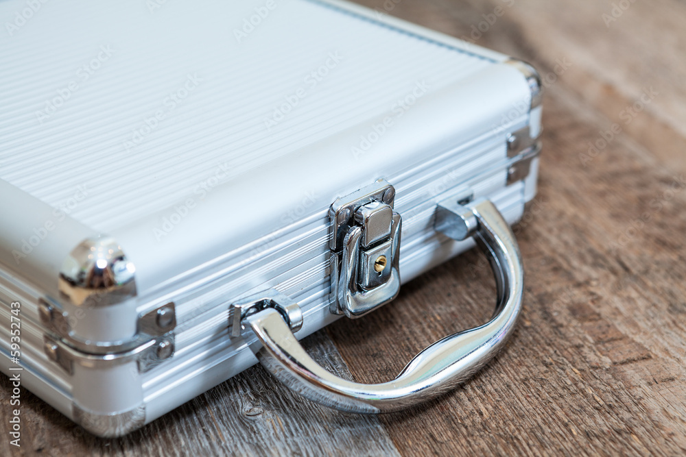 Steel closed briefcase lying on wooden floor Steel closed briefcase lying on wooden floor