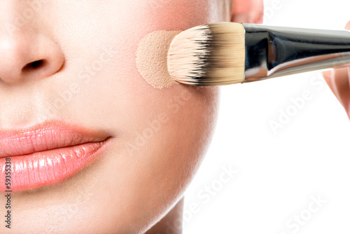 Fotografie Makeup artist applying liquid tonal foundation  on the face