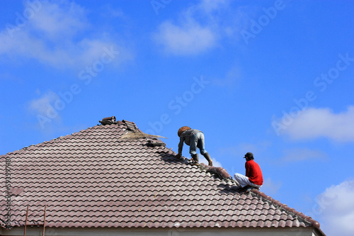 Workers   repair  concrete  roof  tile