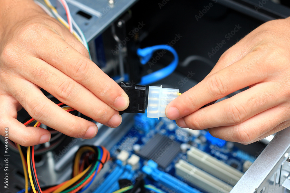 Closeup of a technician's hands wiring a computer mainboard