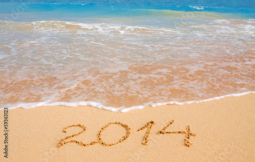  Year 2014 written in sand on tropical beach .