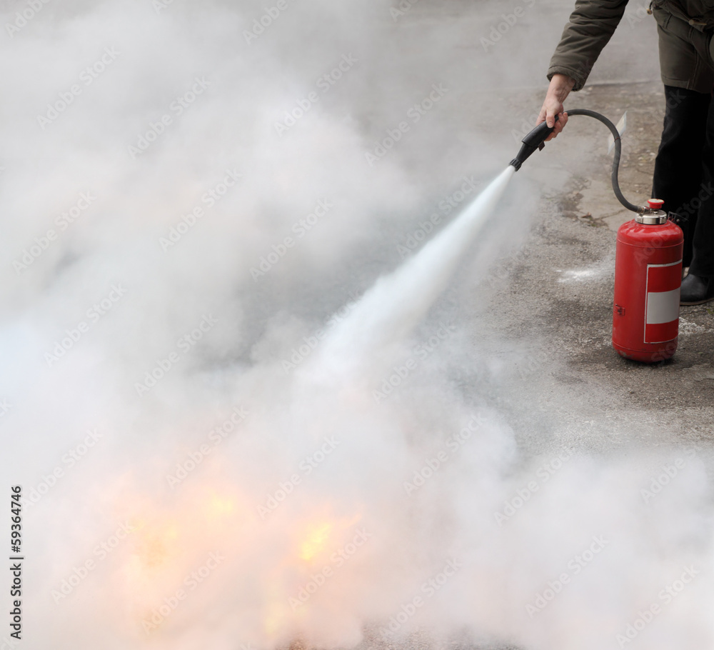 Fototapeta premium Fire fighting woman demonstrating how to use a fire extinguisher