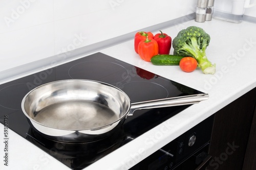 Frying pan and vegetables in modern with induction stove