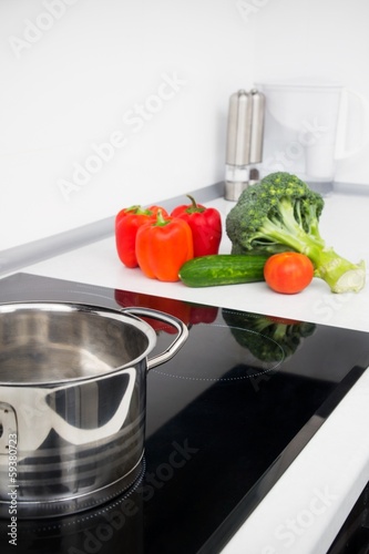 Pot and vegetables in modern kitchen with induction stove