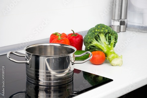 Pot and vegetables in modern kitchen with induction stove