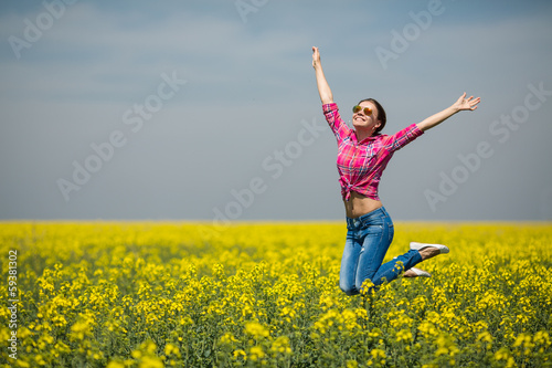 Young beautiful woman in flowering field in summer. Outdoors