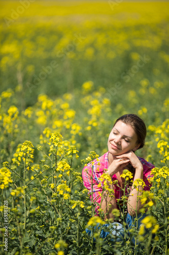 Young beautiful woman in flowering field in summer. Outdoors