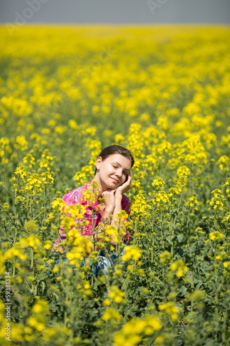 Young beautiful woman in flowering field in summer. Outdoors