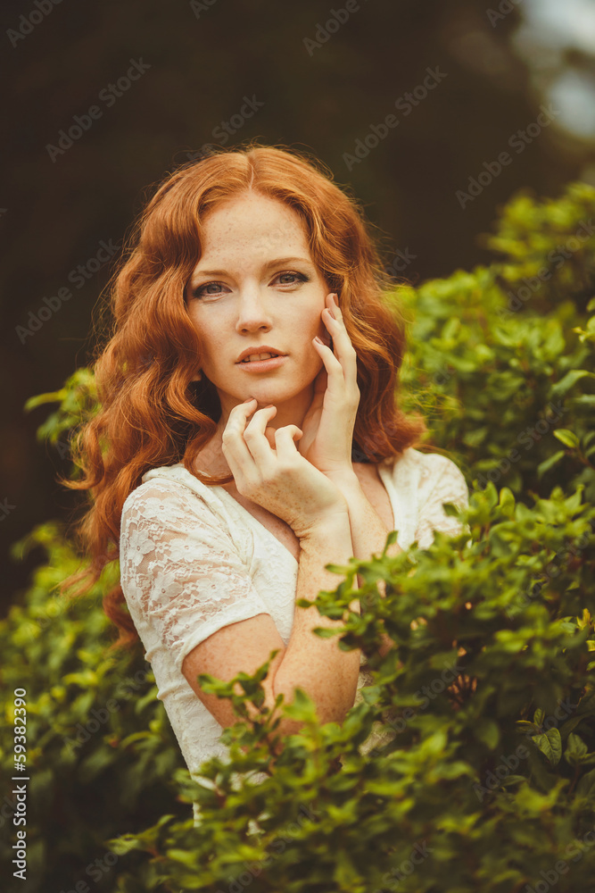 Portrait of young beautiful redhair woman standing in green park