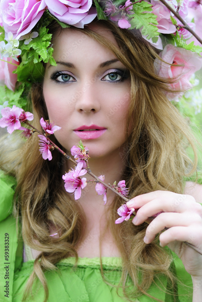 Fototapeta premium Beautiful girl in a flowered garden peach