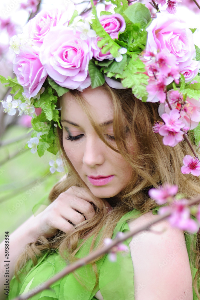 Fototapeta premium Beautiful girl in a flowered garden peach
