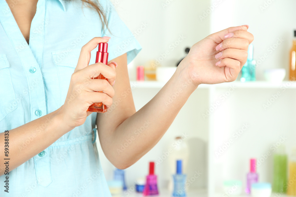 Fototapeta premium Woman testing perfume on shop windows background