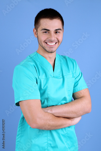 Young male doctor on blue background