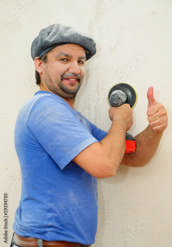 Smiling construction worker hand-polishing the wall photo