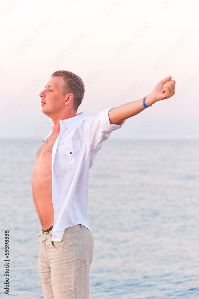 bare-chested man stretching on sea background bare-chested man stretching on sea background