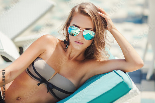 Beautiful woman resting near swimming pool on tropical resort photo