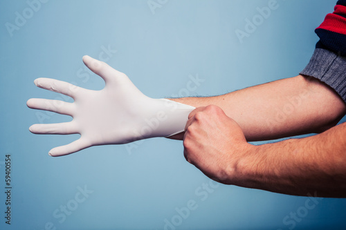 Man putting on latex surgical glove