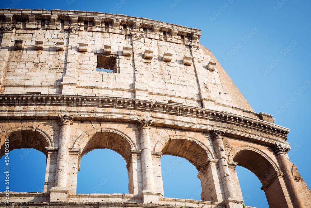 Fragment of the Coliseum against the blue sky. Italy
