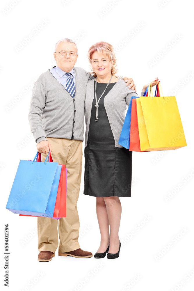 Mature man and woman holding shopping bags and looking at camera Mature man and woman holding shopping bags and looking at camera