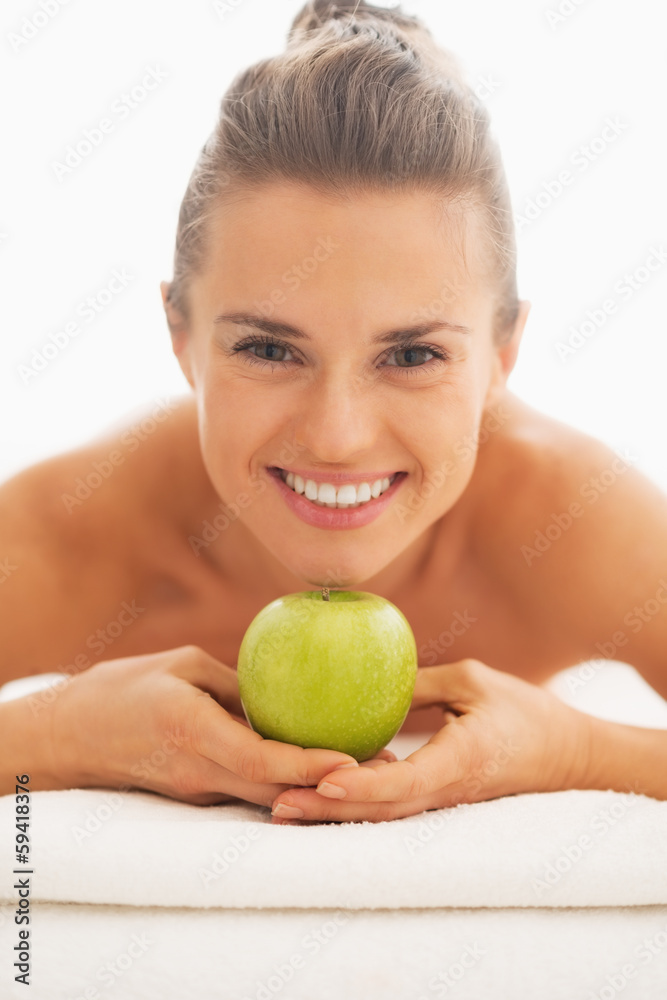 Portrait of young woman on massage table showing apple Portrait of young woman on massage table showing apple