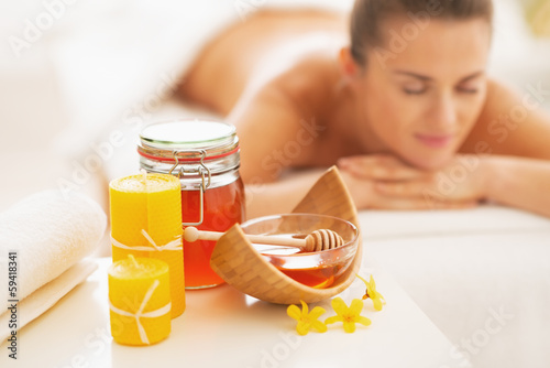 Closeup on honey spa therapy ingredients and woman in background photo
