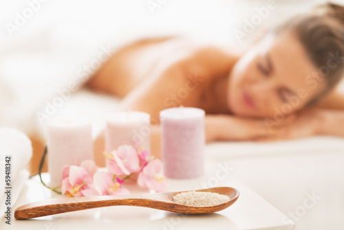Closeup on spa therapy ingredients and woman in background