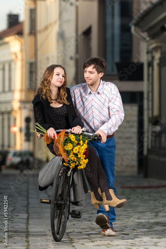 young man pushing his girlfriend on the bicycle