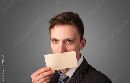 Businessman holding white card at front of her lips with copy sp