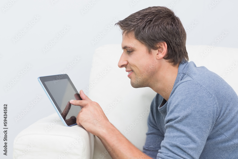 Smiling young man using digital tablet in living room Smiling young man using digital tablet in living room