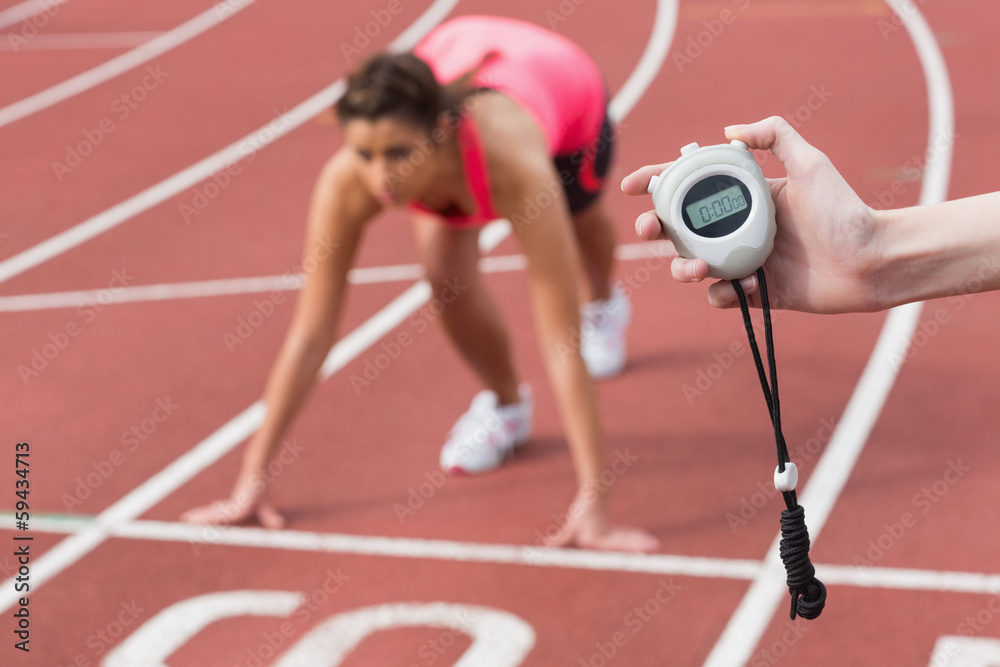 Fototapeta premium Hand timing a woman's run on the running track