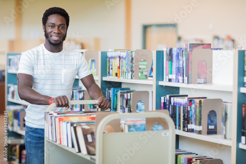 Librarian With Trolley Of Books In Bookstore