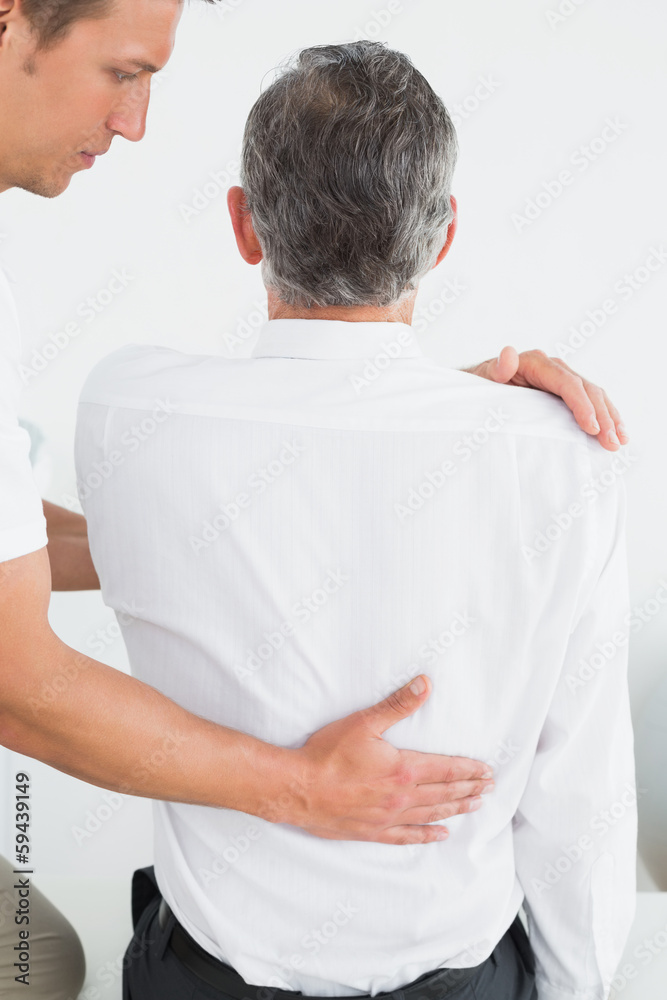 Obraz premium Male chiropractor examining mature man