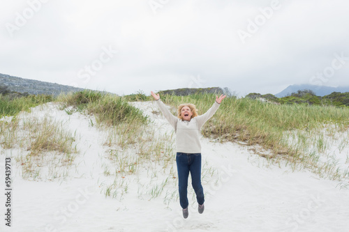 Senior woman jumping at the beach