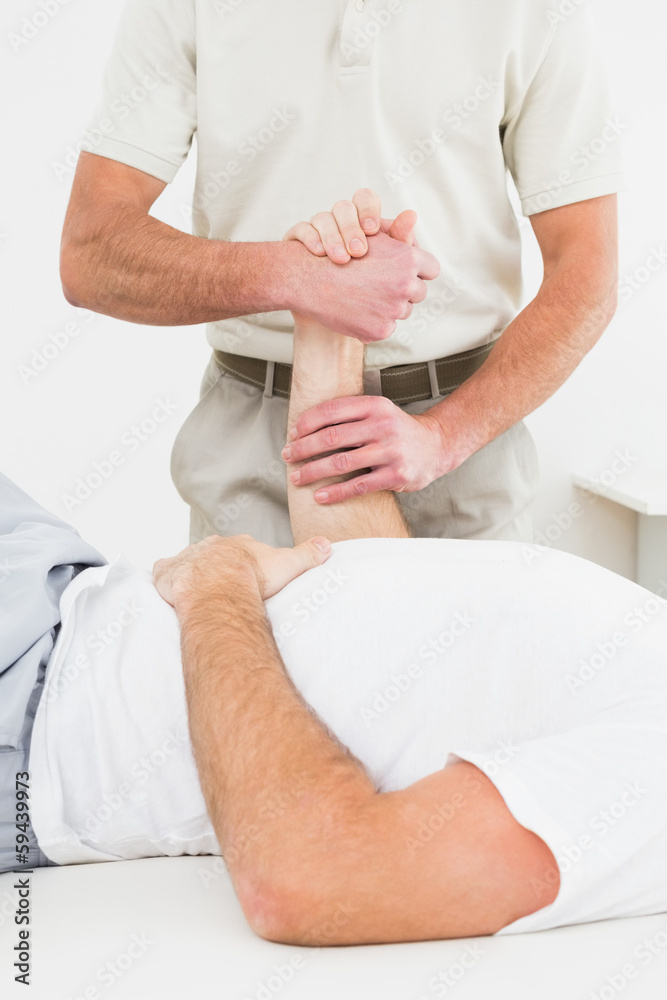 Mid section of physiotherapist examining a man's hand