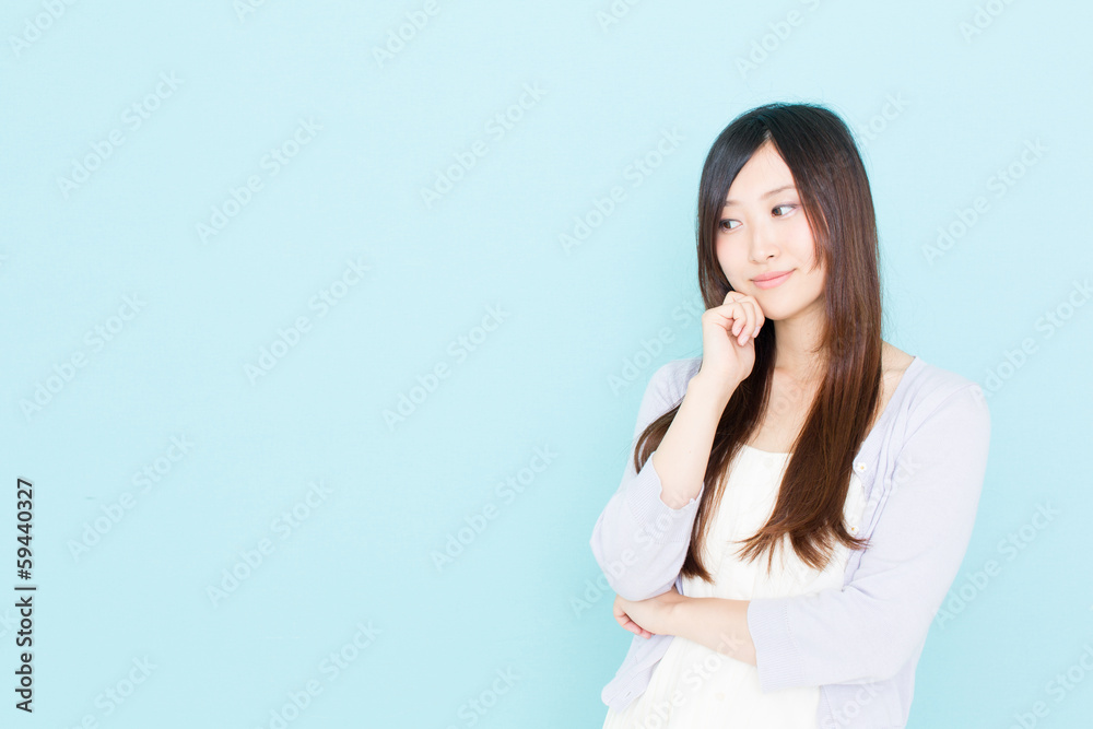 young asian woman thinking on blue background young asian woman thinking on blue background