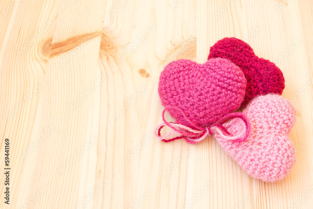 knitted toys in the shape of hearts on a wooden texture
