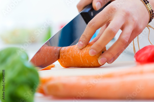 Woman hand cutting carrots in kitchen