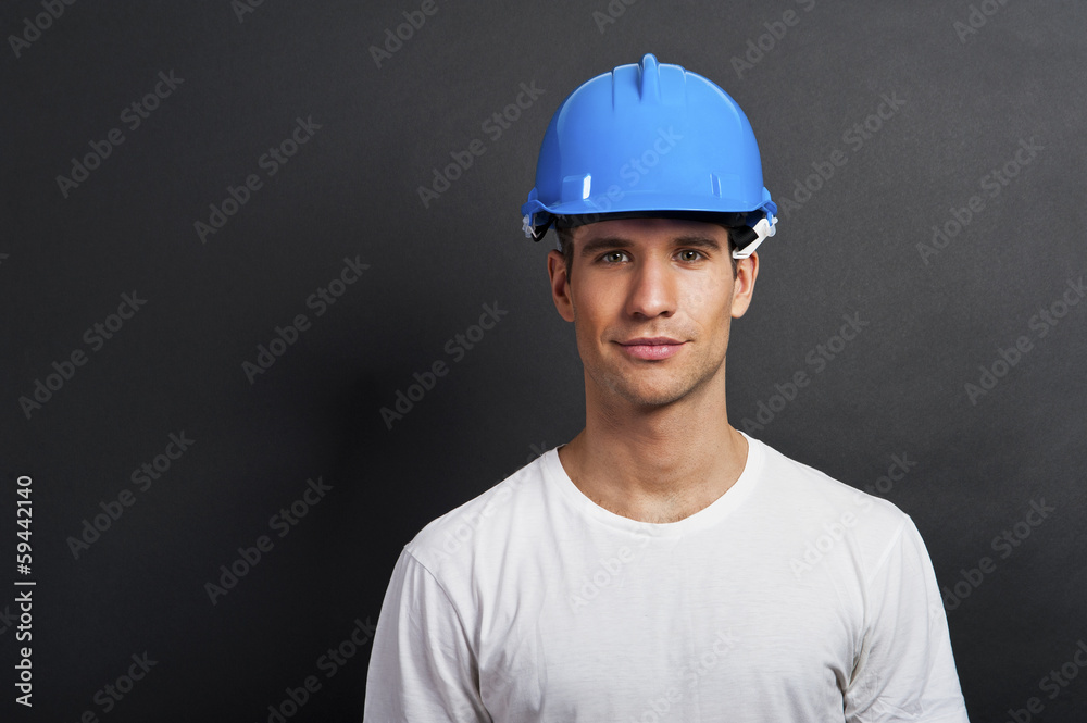 Young construction worker in hard hat on dark background