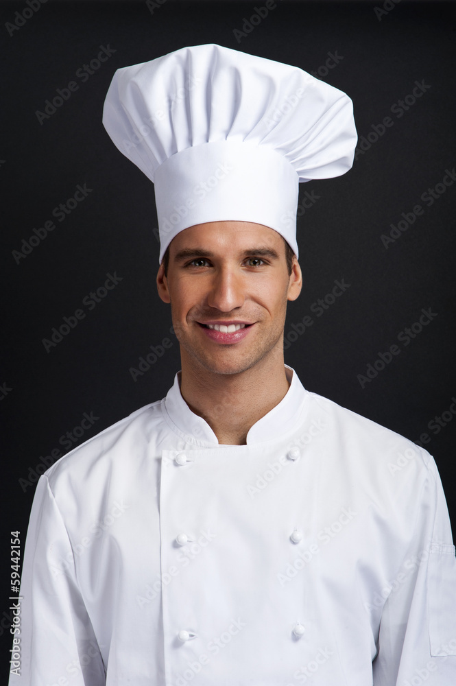 Chef cook against dark background smiling with hat Chef cook against dark background smiling with hat