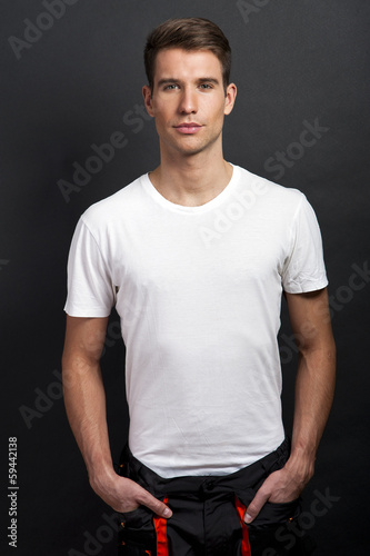 Handsome man posing in white tshirt on dark background in studio © Wisiel