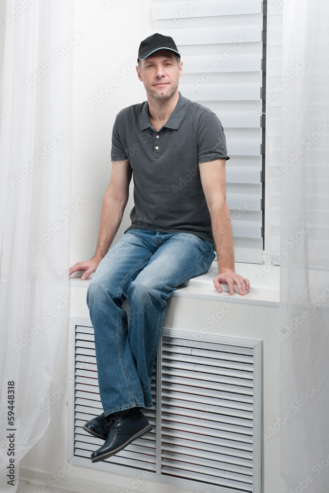 young smiling man sitting on a white window young smiling man sitting on a white window