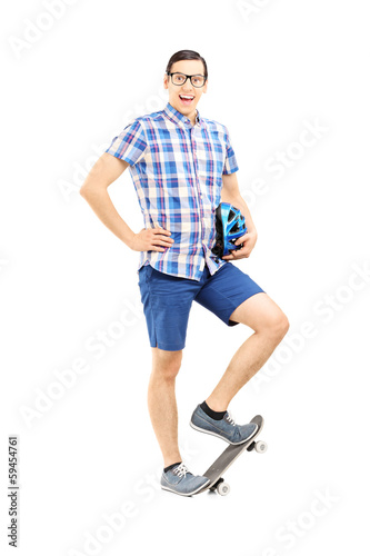 Smiling guy holding a helmet and standing on a skate board