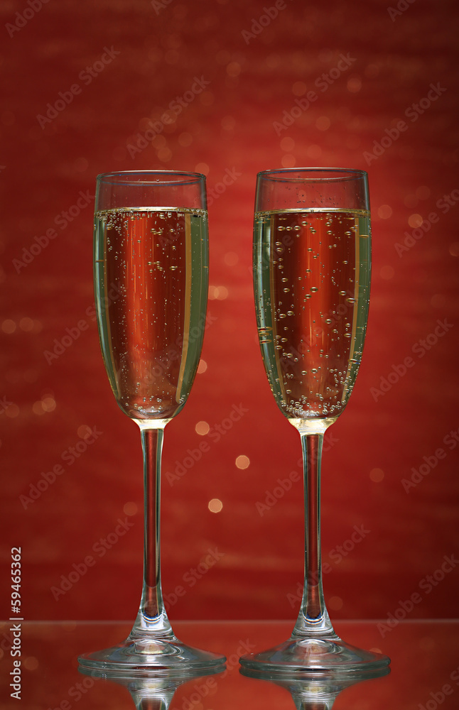 Two glasses of champagne on bright background with lights