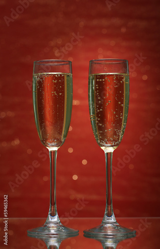 Two glasses of champagne on bright background with lights