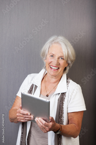 ältere dame mit tablet-pc vor grauer wand