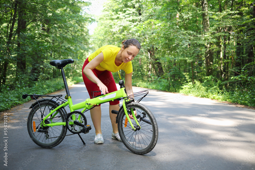 Young woman in sport clothes converts bicycle handle bar in park